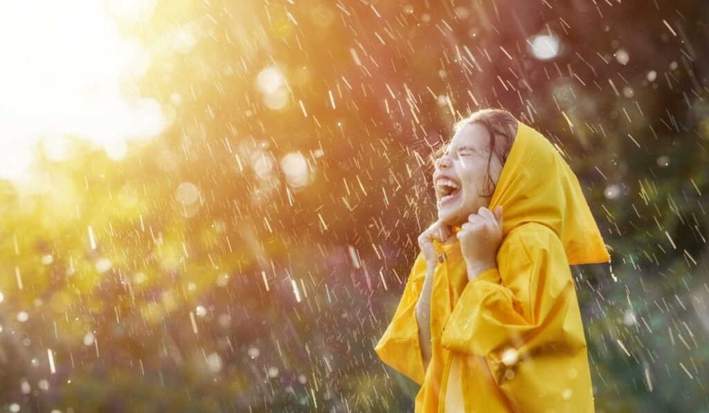 黄色のレインコート着て、雨に打たれる女の子